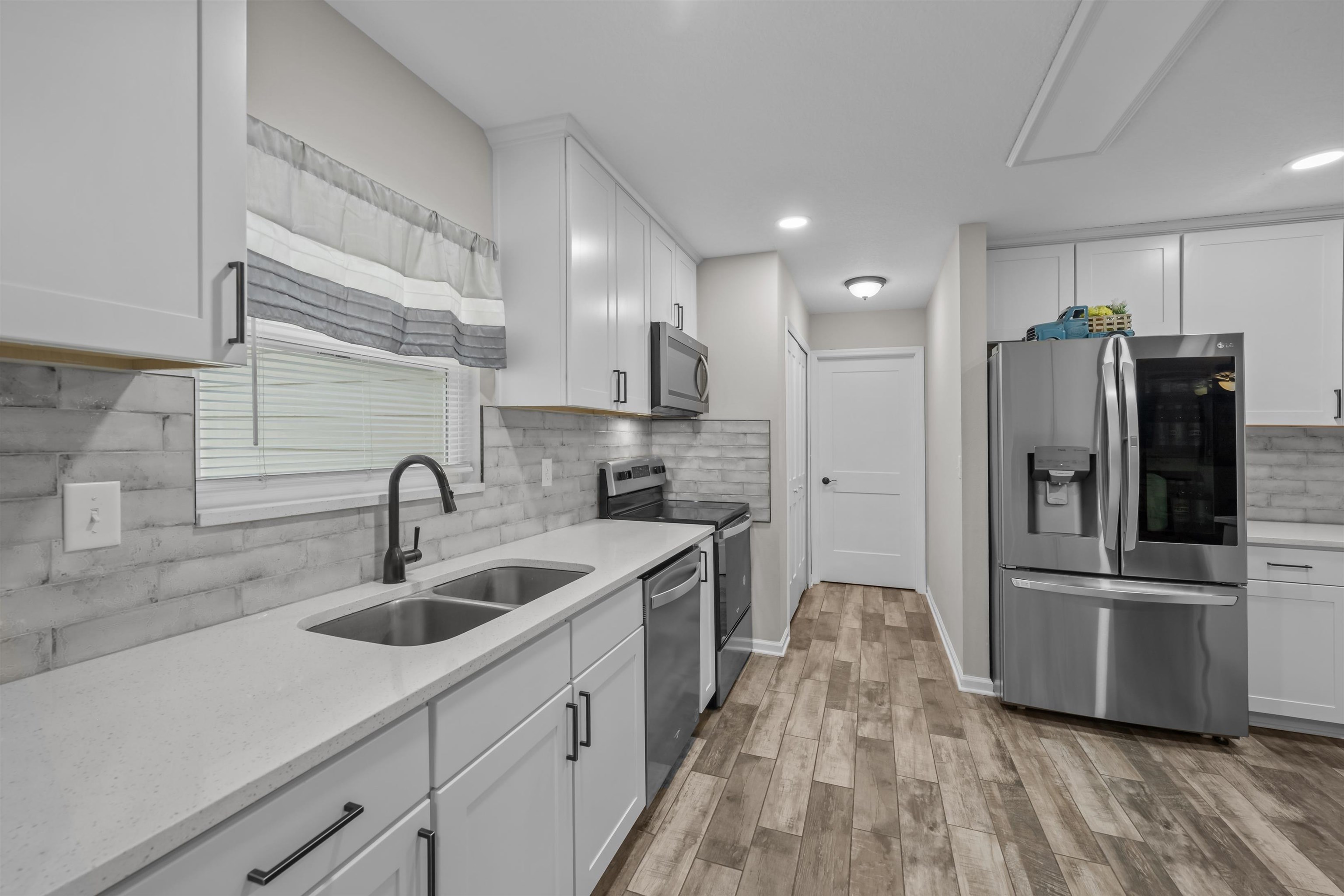232 Kyte Road San Mateo, FL 32187 - Photo 12 of 36 Kitchen with stainless steel appliances, white cabinets, light stone counters, and recessed lighting
