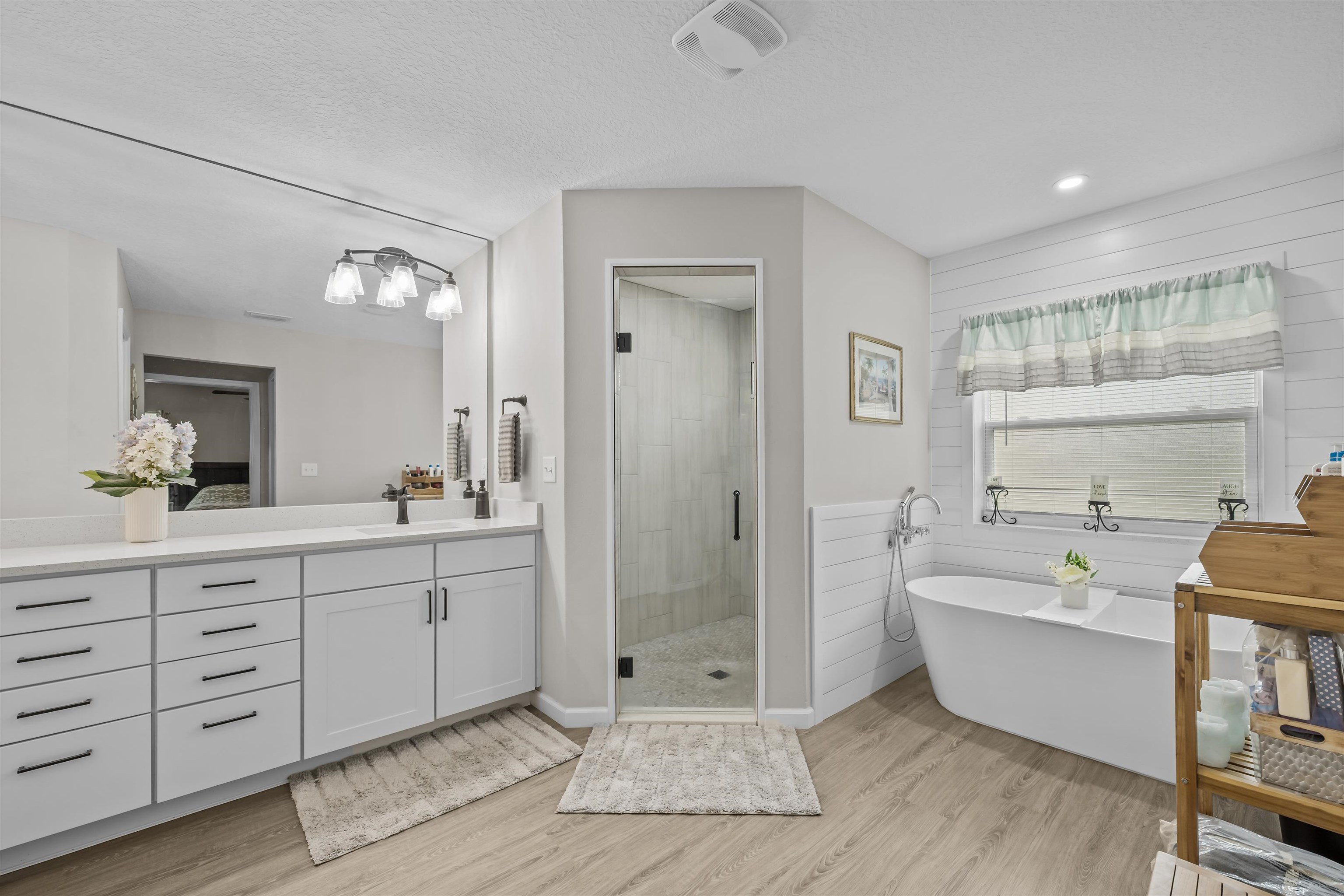 232 Kyte Road San Mateo, FL 32187 - Photo 19 of 36 Bathroom featuring a textured ceiling, a stall shower, a freestanding bath, vanity, and light wood finished floors