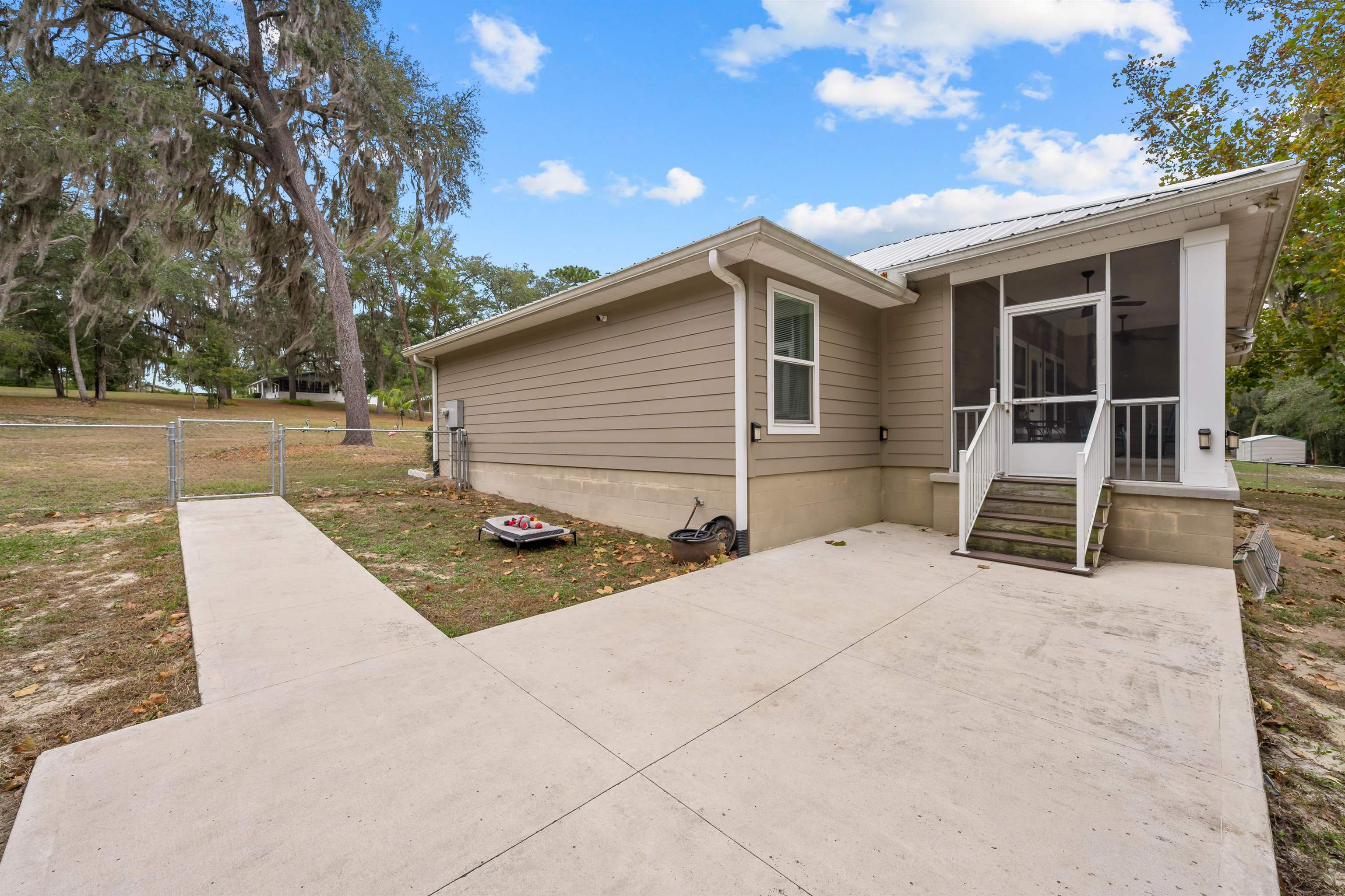 232 Kyte Road San Mateo, FL 32187 - Photo 28 of 36 View of property exterior featuring a sunroom, a gate, a metal roof, and a patio area