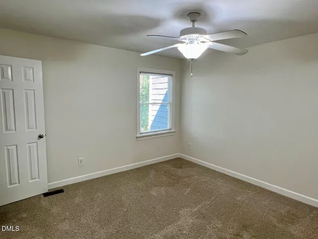 an empty room with a chandelier fan and windows