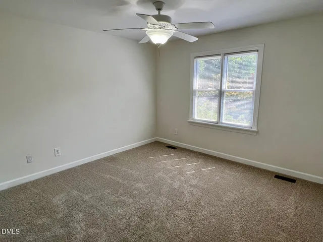an empty room with a window and a fan