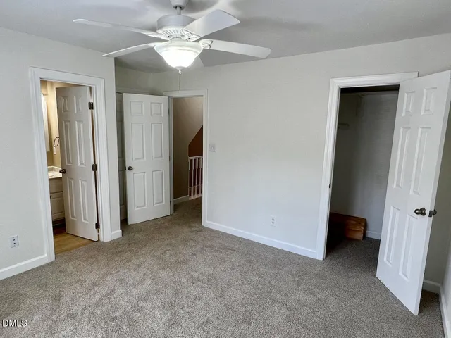 an empty room with closet and a ceiling fan