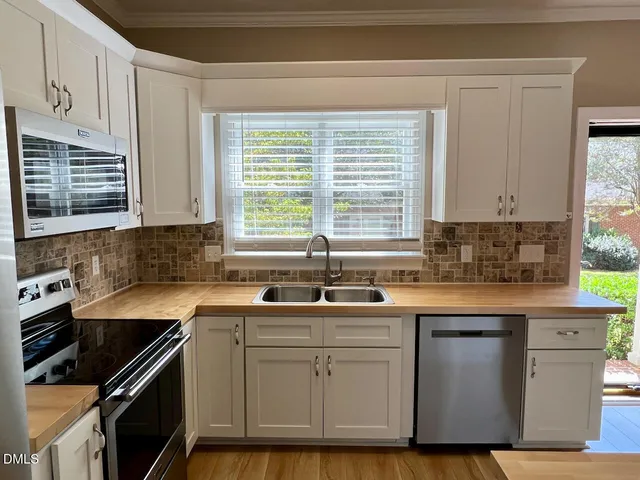 a kitchen with cabinets appliances a sink and a window