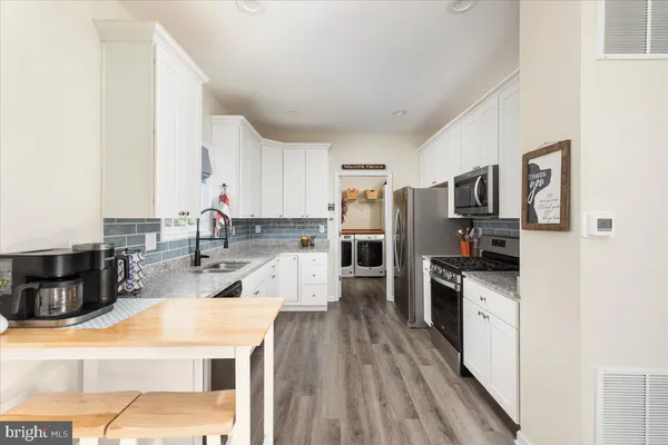 a large kitchen with stainless steel appliances granite countertop a lot of counter space and wooden floors