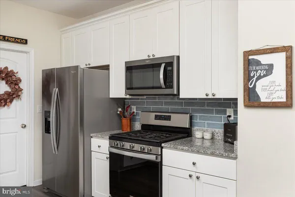 a kitchen with granite countertop a stove microwave and refrigerator