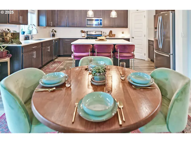 a living room with stainless steel appliances furniture a rug and a kitchen view