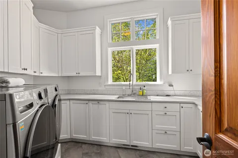 a kitchen with stainless steel appliances granite countertop a sink a stove a refrigerator with white cabinets and wooden floor