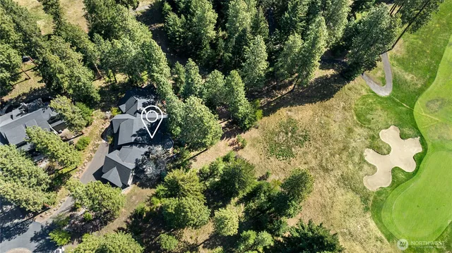 an aerial view of residential house with outdoor space and trees all around
