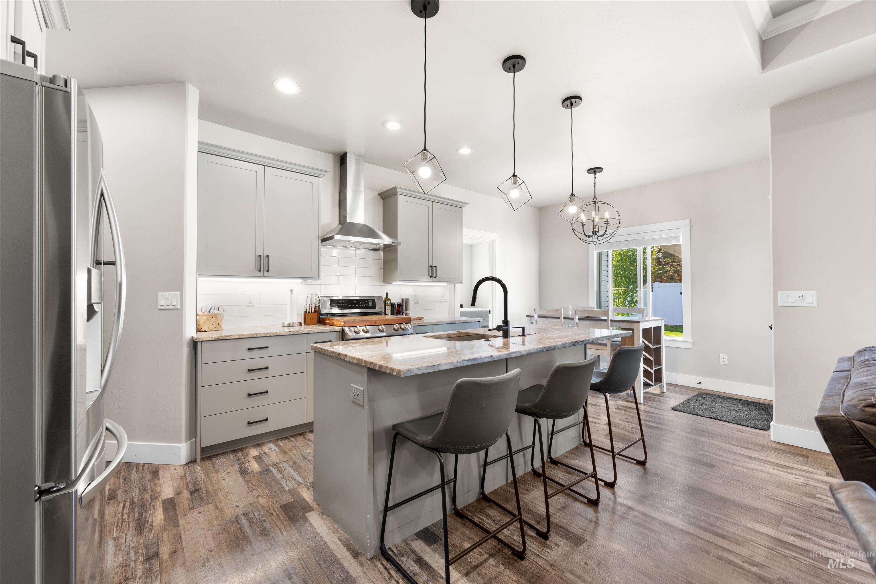 2958 Sunlight Road Twin Falls, ID 83301 - Photo 10 of 40 Modern kitchen featuring light gray cabinetry, stainless steel appliances, a center island with seating, pendant lighting, and wood-finish flooring