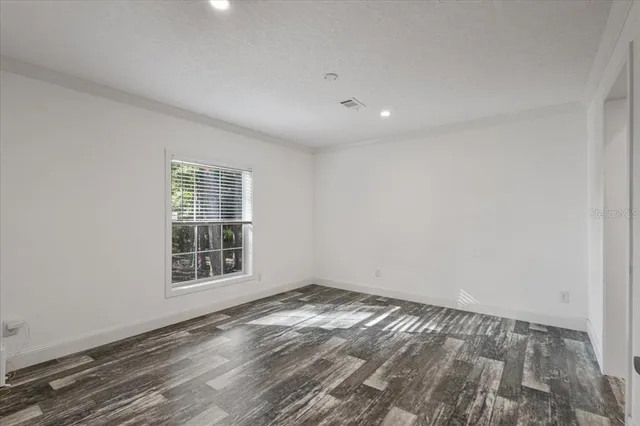 a view of a hallway with wooden floor and a bathroom
