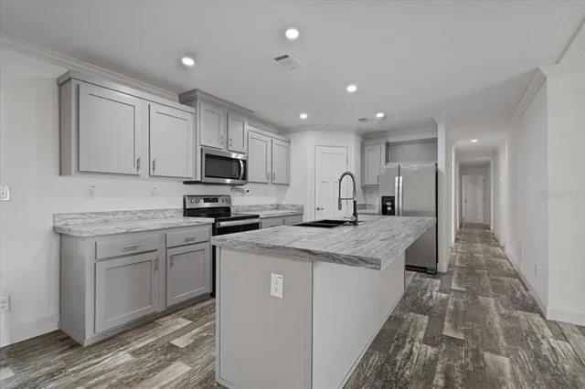 a kitchen with kitchen island a sink stainless steel appliances and white cabinets