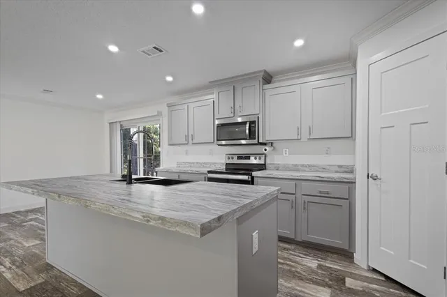 a kitchen with stainless steel appliances granite countertop a stove a sink and a refrigerator