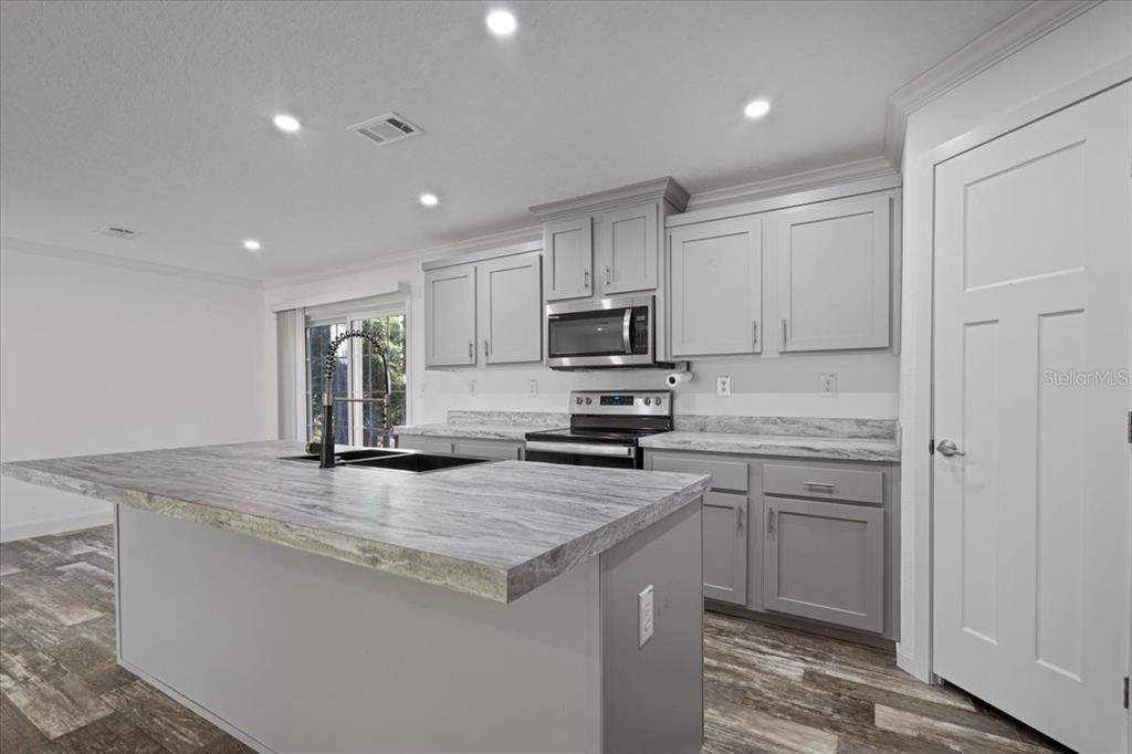 4654 Northwest 45th Avenue Bell, FL 32619 - Photo 8 of 52 a kitchen with kitchen island a sink stainless steel appliances and white cabinets