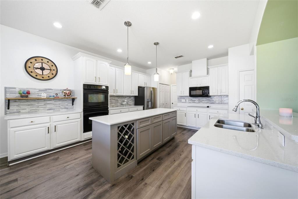 2614 Grapevine Crest Ocoee, FL 34761 - Photo 2 of 24 a large kitchen with stainless steel appliances a white stove top oven a sink dishwasher and a refrigerator with wooden floor