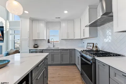 a kitchen with stainless steel appliances a sink dishwasher stove refrigerator and cabinets with wooden floor