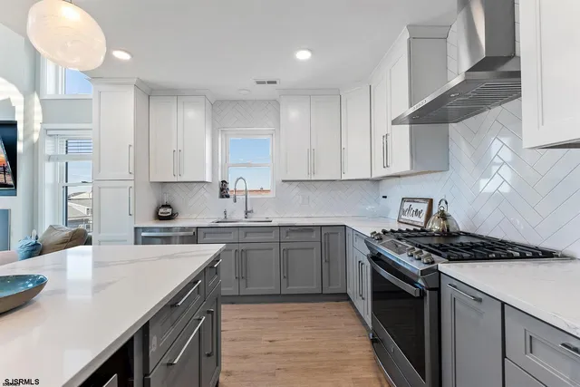 a kitchen with stainless steel appliances a sink dishwasher stove refrigerator and cabinets with wooden floor