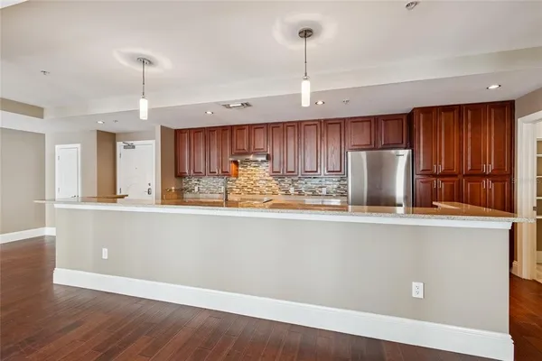 a kitchen with stainless steel appliances granite countertop a refrigerator a stove a sink dishwasher and white cabinets with wooden floor