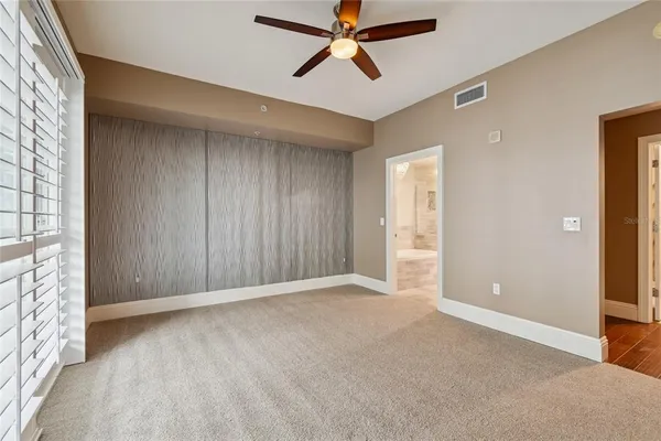 an empty room with windows and ceiling fan