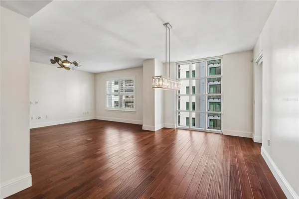 an empty room with wooden floor large windows and couch
