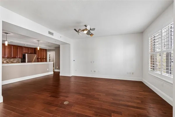 a view of an empty room with wooden floor and a window