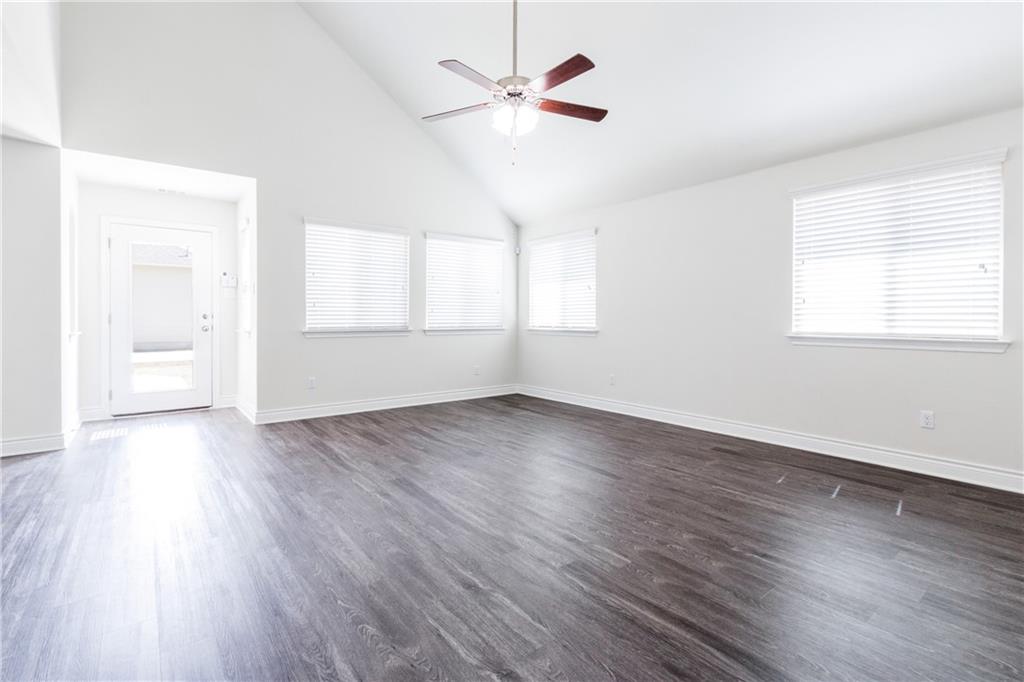 2104 Pindos Pony Way Georgetown, TX 78626 - Photo 7 of 30 A spacious room features vaulted ceilings and wood flooring, perfect for versatile living.