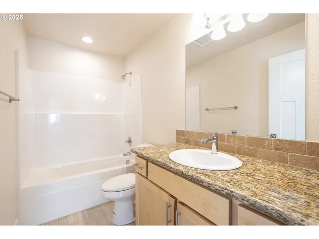 a bathroom with a granite countertop sink toilet a mirror and shower