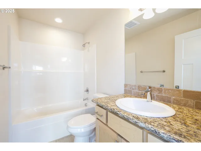 a bathroom with a granite countertop sink a toilet a mirror and bathtub