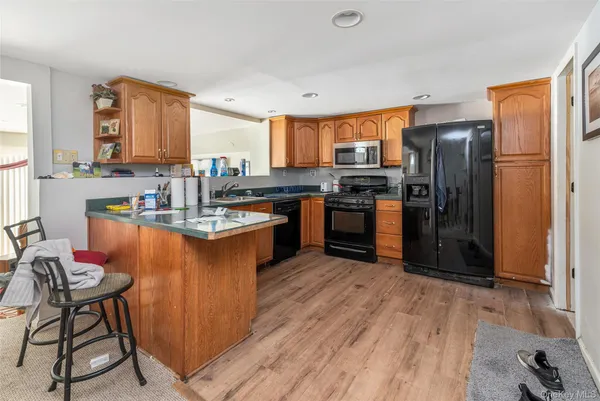 a kitchen with stainless steel appliances granite countertop a refrigerator a stove a sink dishwasher and a refrigerator with wooden floor