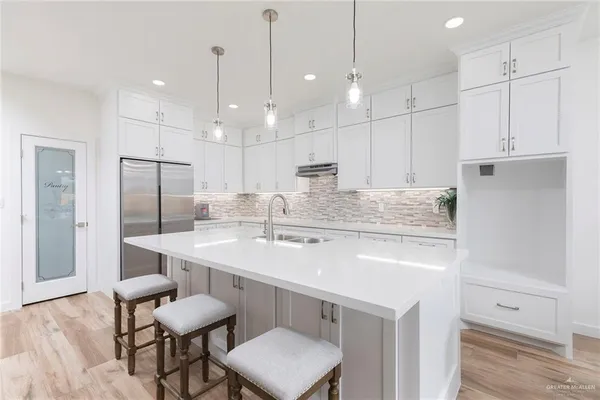 a kitchen with a sink a center island stainless steel appliances and cabinets