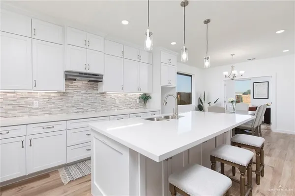 a kitchen with kitchen island a white counter space a sink appliances and cabinets