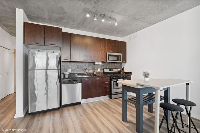 a kitchen with a refrigerator a stove top oven a sink dishwasher and wooden floor