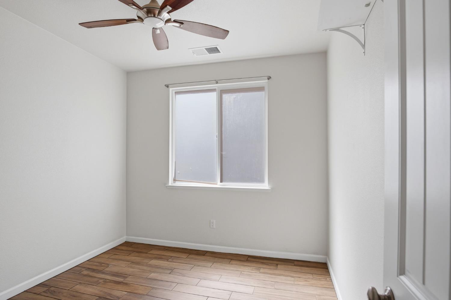 4113 Snowfire Drive Modesto, CA 95357 - Photo 12 of 19 an empty room with wooden floor fan and windows