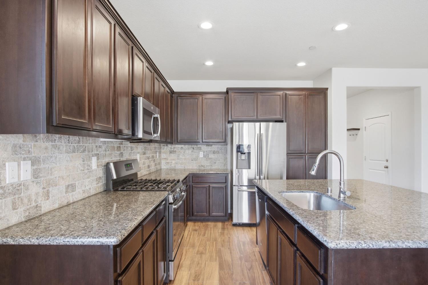 4113 Snowfire Drive Modesto, CA 95357 - Photo 6 of 19 a kitchen with stainless steel appliances granite countertop a sink a stove and a refrigerator