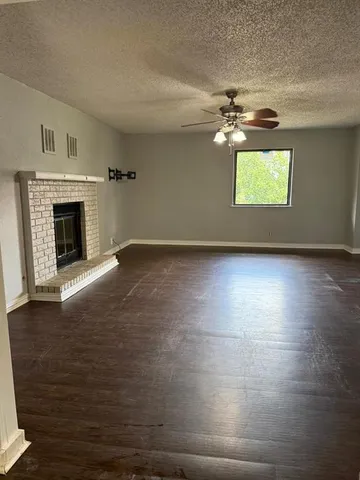 an empty room with wooden floor fireplace and windows