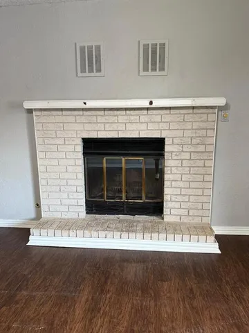 a view of an empty room with wooden floor and a fireplace