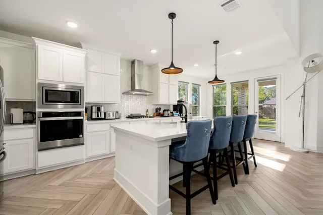 a kitchen with stainless steel appliances kitchen island granite countertop a stove a sink a microwave a refrigerator with a dining table and chairs