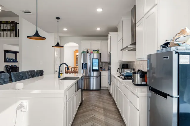 a kitchen with refrigerator a sink and wooden floor
