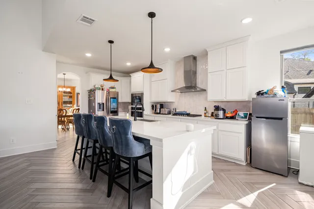 a kitchen with stainless steel appliances granite countertop a refrigerator a stove a sink dishwasher a dining table and chairs with wooden floor