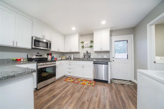 a kitchen with granite countertop a refrigerator stove top oven and sink
