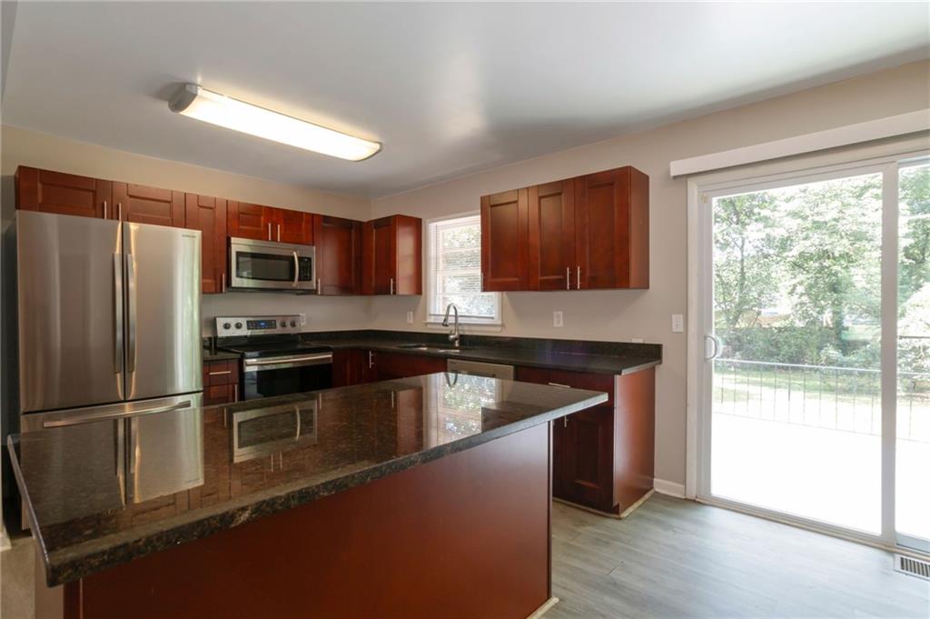 904 Pine Roc Drive Stone Mountain, GA 30083 - Photo 7 of 15 a kitchen with kitchen island granite countertop stainless steel appliances a sink and a refrigerator