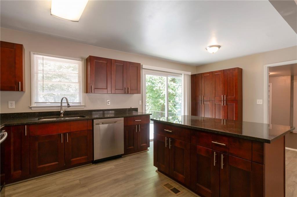 904 Pine Roc Drive Stone Mountain, GA 30083 - Photo 8 of 15 a kitchen with granite countertop wooden cabinets a sink and a window