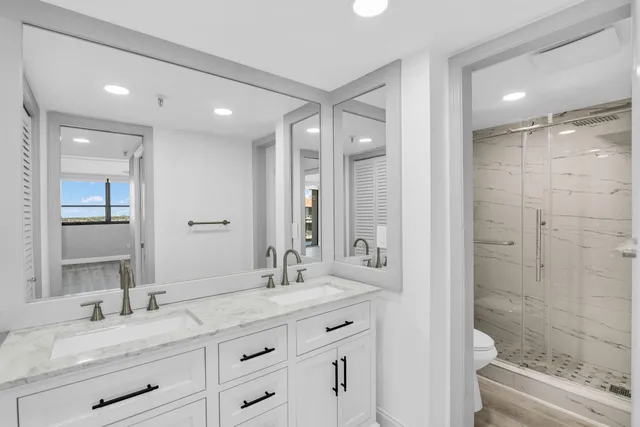 a bathroom with a granite countertop sink a toilet a shower and a mirror