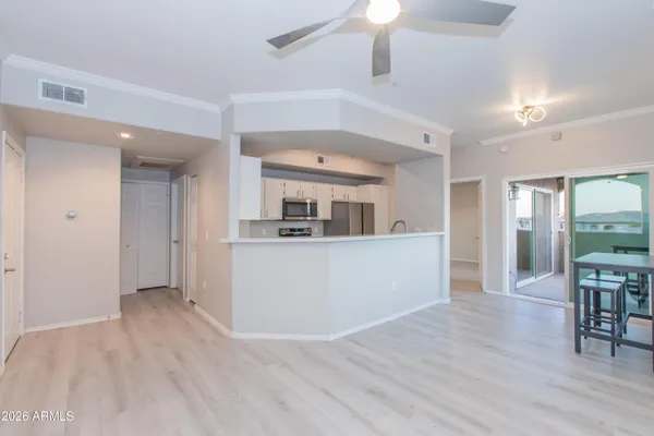 an empty room with wooden floor fan and windows