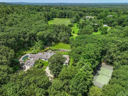 an aerial view of residential house with outdoor space and trees all around