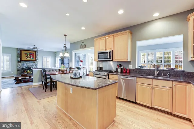 a large kitchen with cabinets a sink a counter and chairs in it