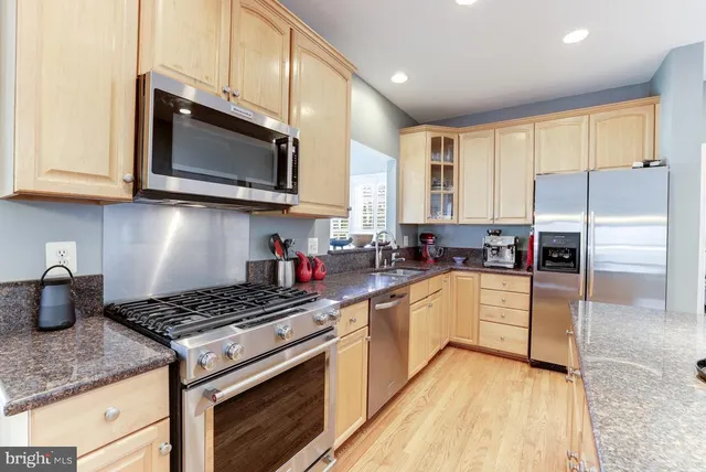 a kitchen with stainless steel appliances granite countertop a stove microwave sink and refrigerator