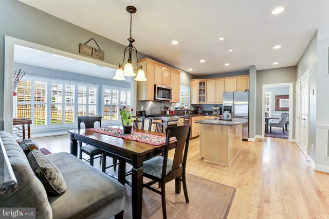 a dining room with stainless steel appliances granite countertop a table chairs and a chandelier