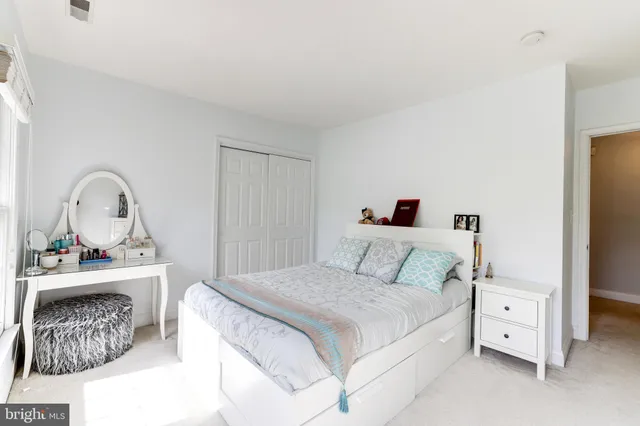 a bedroom with a bed flat screen tv and windows