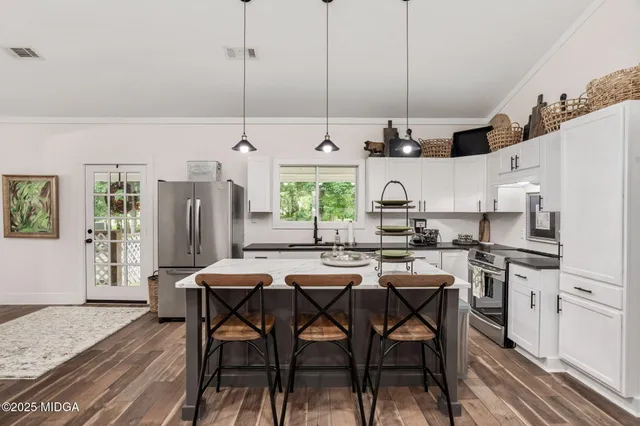 a kitchen with stainless steel appliances granite countertop a kitchen island a stove a table and chairs