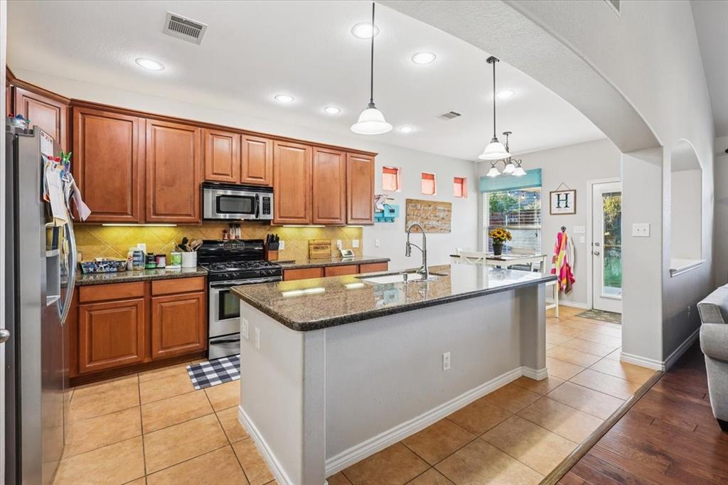 868 Valley Ridge Road Burleson, TX 76028 - Photo 7 of 39 a kitchen with stainless steel appliances granite countertop a sink a stove and a refrigerator